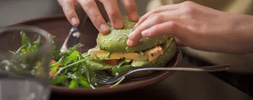 Une personne mangeant un hamburger végatal.
